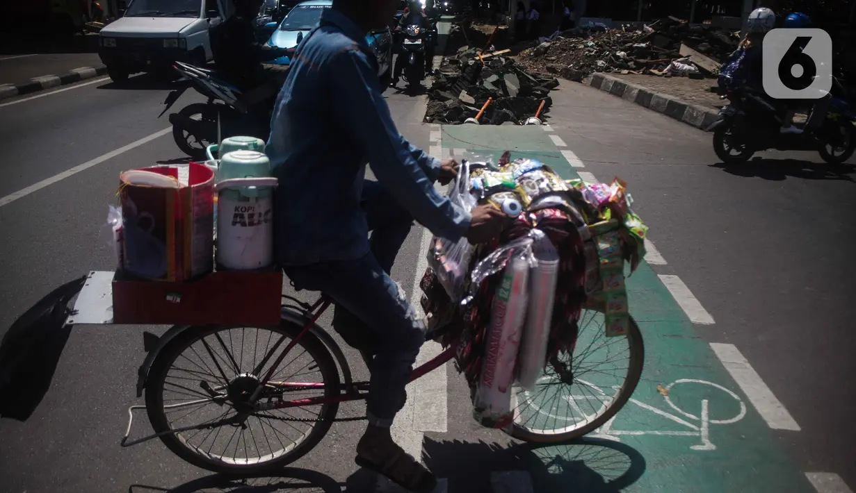 Pengguna jalan melintas di samping jalur sepeda yang di bongkar di kawasan Cikini, Jakarta, Selasa (19/11/2019). Jalur sepeda berumur 2 bulan tersebut dibongkar akibat proyek pelebaran trotoar. (Liputan6.com/Faizal Fanani)