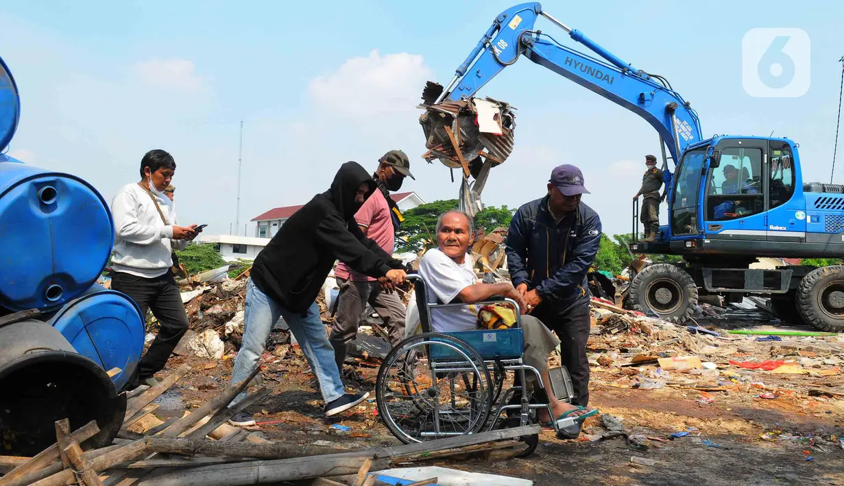 Warga melintas dekat alat berat saat menghancurkan bangunan yang terdampak proyek sodetan Ciliwung menuju Kanal Banjir Timur (KBT) di Kelurahan Cipinang Besar Selatan, Jakarta, Kamis (12/1/2023). Warga ber-KTP DKI Jakarta akan direlokasi ke rumah susun Cipinang Besar Utara, sedangkan para pedagang akan ditempatkan di pasar PD Pasar Jaya. (merdeka.com/Imam Buhori)