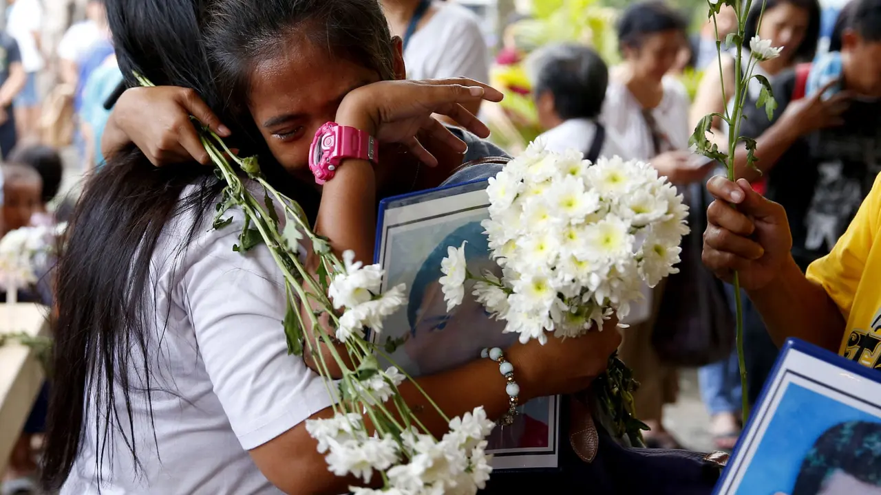 Kerabat korban korban penumpasan narkoba Presiden Rodrigo Duterte satu sama lain di pemakaman di kota Quezon pada bulan Maret. (AP/Bullit Marquez)