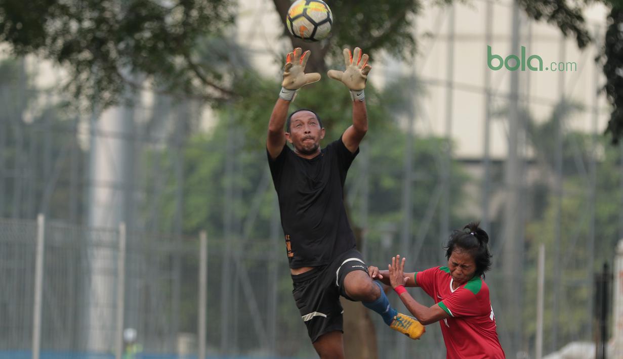 Aksi pemain Timnas Wanita Indonesia, Tugiati (kanan) berebut bola dengan kiper Legenda Indonesia pada laga uji coba di Lapangan ABC Senayan, Jakarta, Kamis (5/4/2018). Timnas Wanita Indonesia menang 3-2. (Bola.com/Nick Hanoatubun)