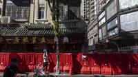 Seorang penduduk melewati barang-barang melintasi penghalang sementara yang didirikan untuk menutup blok perumahan yang dianggap berisiko tinggi terinfeksi Covid-19 di Guangzhou di provinsi Guangdong, China selatan, Rabu (9/11/2022). Lonjakan kasus COVID-19 telah mendorong penguncian di pusat manufaktur China selatan Guangzhou, menambah tekanan keuangan yang telah mengganggu rantai pasokan global dan secara tajam memperlambat pertumbuhan di ekonomi terbesar kedua di dunia itu. (Chinatopix via AP)