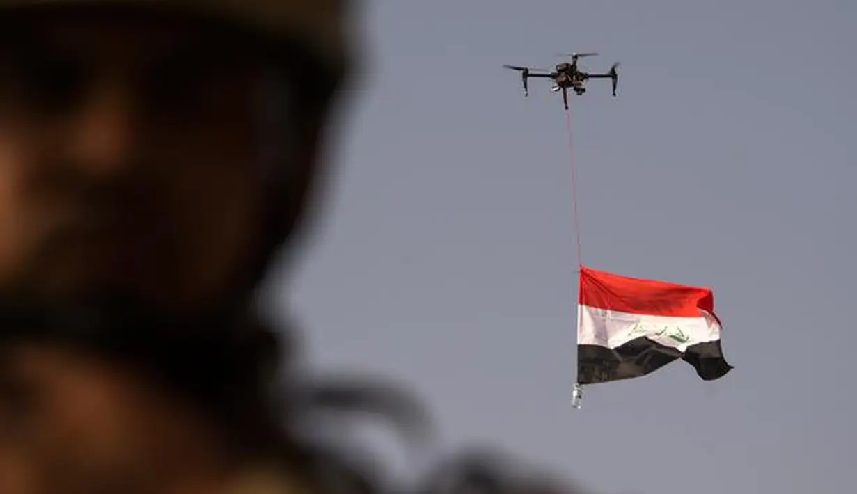 Sebuah drone mengibarkan bendera nasional Irak saat perayaan keberhasilan menyingkirkan militan ISIS dari Kota Tua Mosul, Minggu (9/7). Irak memulai pertempuran merebut Mosul pada Oktober lalu dengan dukungan dari koalisi pimpinan AS. (FADEL SENNA/AFP)