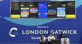 Para penumpang duduk di depan papan informasi yang menunjukkan lokasi meja maskapai di Bandara Gatwick dekat London, Inggris, Kamis 12 Juni 2025. (AP/Kin Cheung)
