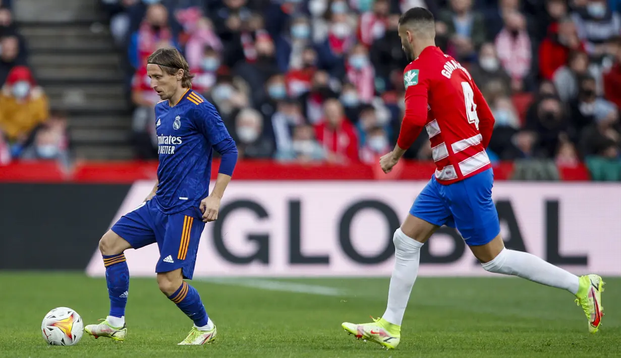 Gelandang Real Madrid Luka Modric berebut bola dengan gelandang Granada Maxime Gonalons dalam laga lanjutan Liga Spanyol di Stadion Nuevo Los Carmenes, Senin (22/11/2021) dini hari WIB.  Real Madrid menang telak dengan skor 4-1 atas tuan rumah Granada. (AP Photo/Fermin Rodriguez)