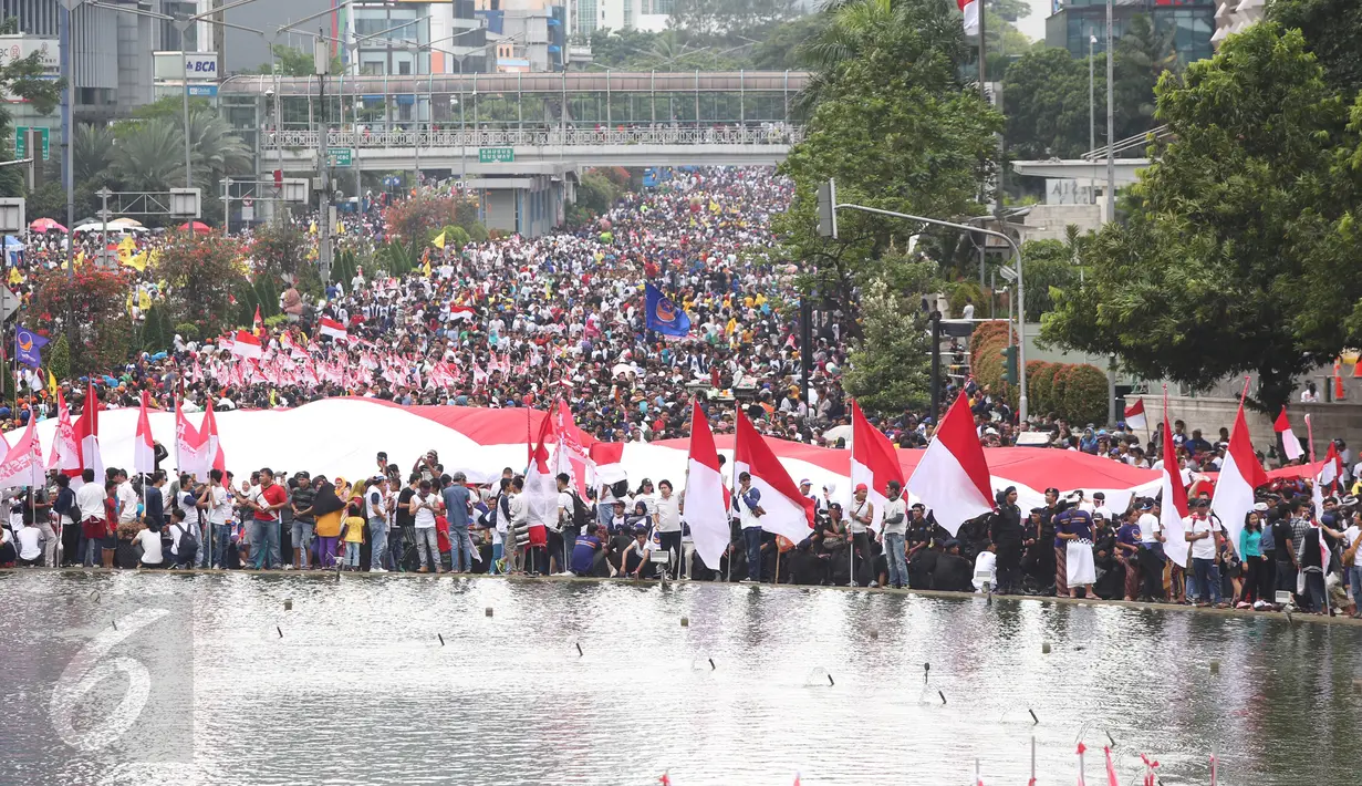 Ribuan massa berkumpul memeriahkan aksi damai 'Kita Indonesia' di Bundaran HI, Jakarta, Minggu (4/12). Sebuah bendera Merah Putih raksasa dibawa berkeliling Bundaran HI oleh sejumlah warga sambil meneriakkan 'Kita Indonesia'. (Liputan6.com/Fery Pradolo)