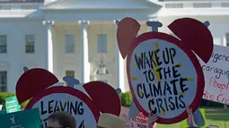 Demonstran membawa poster saat aksi di dekat Gedung Putih di Washington, AS, Kamis (1/6). Demonstran memprotes keputusan Donald Trump yang menarik AS dari perjanjian Paris tentang perubahan iklim yang disepakati pada 2015. (AP/ Susan Walsh)