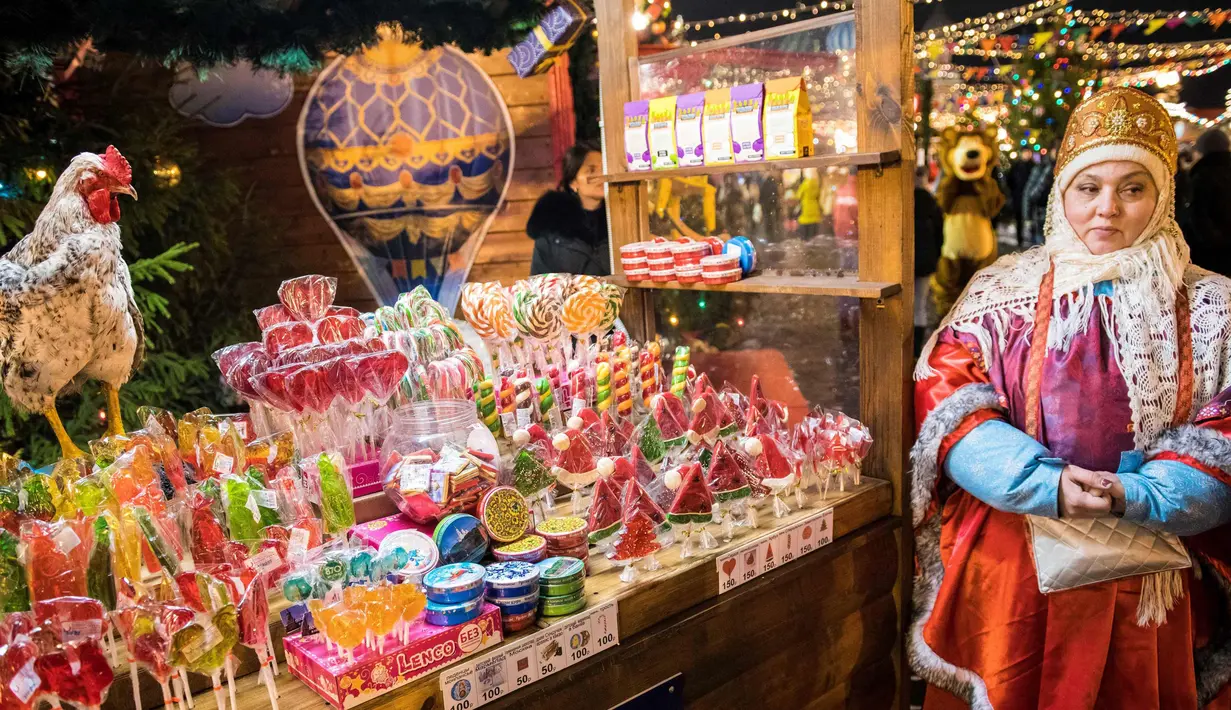 Seorang pedagang mengenakan pakaian tradisional menjual permen di pasar Natal di Lapangan Merah di Moskow (4/12). (AFP Photo/Mladen Antonov)