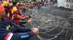 Massa merusak pagar berduri saat berunjuk rasa di depan Gedung DPR, Senayan, Jakarta, Selasa (14/3/2023). Imbas aksi demo tersebut, kepolisian mengimbau kepada para pengguna jalan untuk mencari jalan alternatif guna menghindari kemacetan. (Liputan6.com/Johan Tallo)