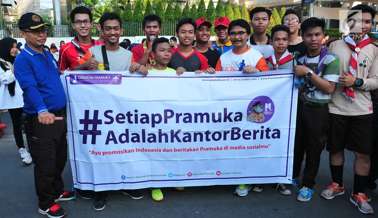 Sejumlah warga berfoto bersama dengan Ketua Kwartir Nasional (Kwarnas) Gerakan Pramuka Adhyaksa Dault sambil memegang spanduk saat aksi Satu Indonesia di area CFD, Bundaran HI, Minggu (30/7). (Liputan6.com/Helmi Afandi)