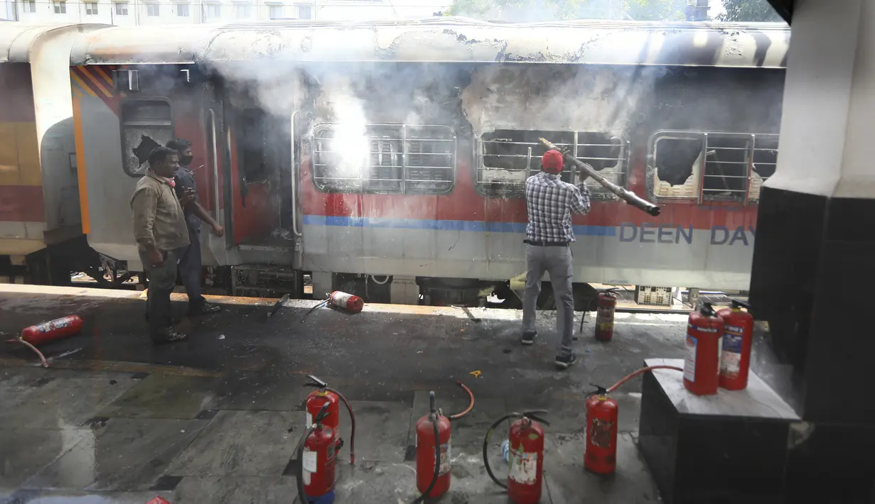 Petugas kereta api memadamkan api di gerbong kereta api di stasiun kereta api Secundrabad di Hyderabad, India, Jumat (17/6/2022). Ratusan pemuda melampiaskan kemarahan dengan membakar gerbong kereta, merusak properti kereta api dan memblokir rel dan jalan raya dengan batu-batu besar sebagai serangan balasan. (AP Photo/Mahesh Kumar A)