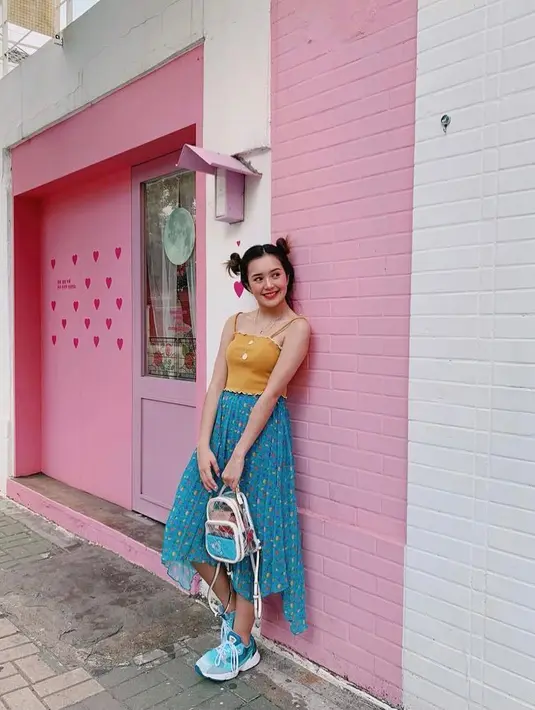 Beby Tsabina tampil manis dengan padu padan tank top warna kuning dengan rok asimetris warna biru. (Instagram/bebytsabina).