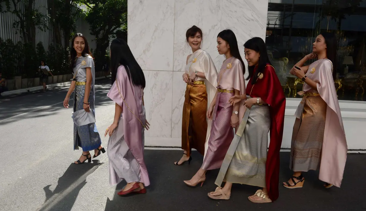 Para pekerja wanita mengenakan kostum tradisional berjalan untuk mengikuti upacara keagamaan Buddha sebagai persiapan festival tahun baru Songkran di luar kantor di Bangkok, Thailand (9/4). (AFP Photo/Romeo Gacad)