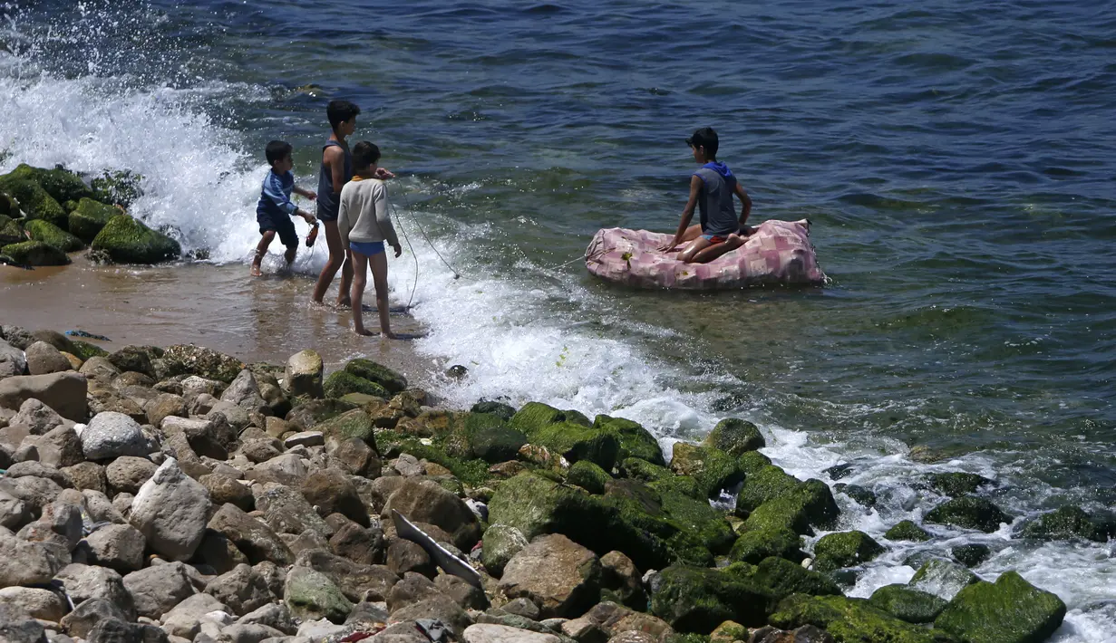 Anak-anak bermain air selama bulan suci Ramadan di pantai Kota Gaza, Palestina, Jumat (1/5/2020). (MOHAMMED ABED/AFP)