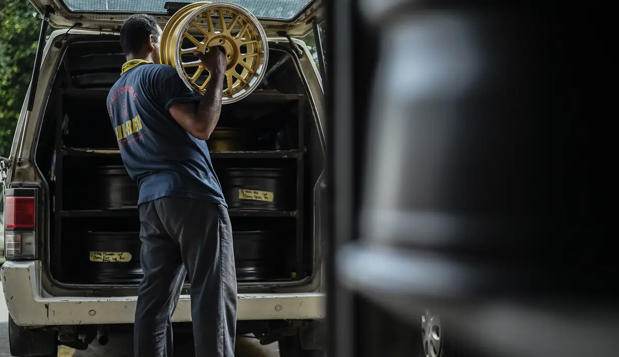 Seorang pekerja mengangkat velg yang telah diperbaharui di sebuah bengkel di Ampang, di pinggiran kota Kuala Lumpur, Malaysia (18/7). (AFP Photo/Mohd Rasfan)