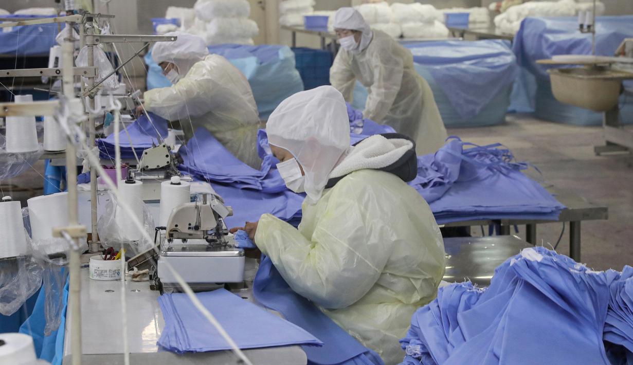 Pekerja memproduksi pakaian pelindung di sebuah pabrik di Nantong, Provinsi Jiangsu, China, Senin (27/1/2020). Pakaian pelindung tersebut diproduksi untuk mendukung pasokan bahan medis saat wabah virus corona melanda China. (STR/AFP)