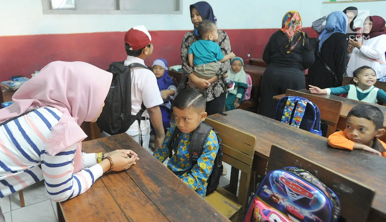 Seorang ibu menenangkan anaknya yang merajuk saat hari pertama masuk sekolah di SDN Cinere 1, Depok, Jawa Barat, Senin (15/7/2019). Seluruh siswa SD, SMP dan SMA, pada hari ini mulai masuk sekolah pada tahun ajaran baru 2019/2020. (merdeka.com/Arie Basuki)