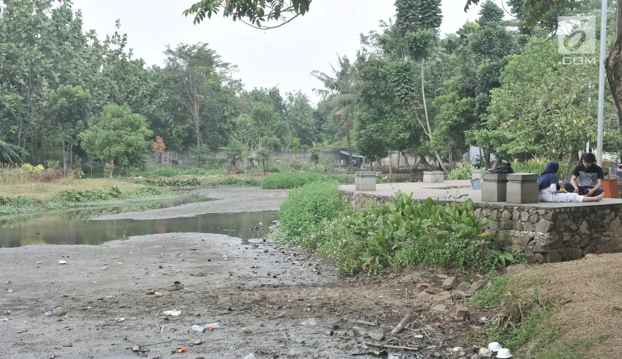 Warga duduk di samping danau yang mengalami kekeringan di Taman Cempaka, Cipayung, Jakarta Timur, Minggu (7/7/2019). Danau buatan yang sedianya berfungsi sebagai penampung air hujan sekaligus wisata pemancingan gratis mengalami kekeringan akibat musim kemarau. (merdeka.com/Iqbal S Nugroho)