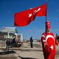 Isikli Tosun Baba (60) memegang dan mengenakan bendera Turki di Oncupinar, Kilis, Turki, Minggu (28/1). (AP Photo/Lefteris Pitarakis)