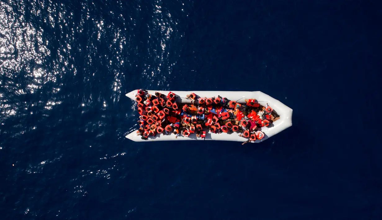 Pengungsi dan imigran mengenakan pelampung saat diselamatkan oleh LSM Proactiva Open Arms Spanyol di utara pantai Libya, Minggu (6/5). Mereka meninggalkan Libya dan mencoba mencapai Eropa. (AP Photo/Felipe Dana)