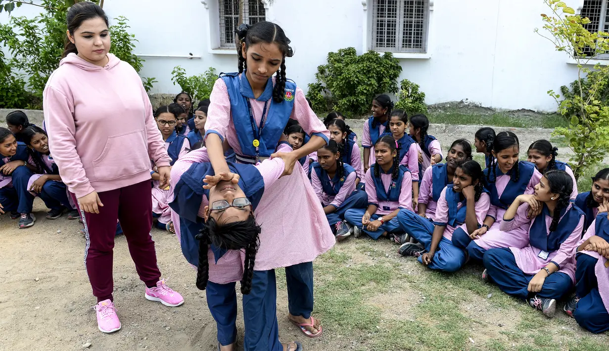 Dua siswi saat belajar bela diri di Telangana Minorities Residential Girls School di Hyderabad, India (17/6/2019). Maraknya kejahatan, kekerasan dan pelecehan seksual yang terjadi terhadap perempuan India membuat pelajaran bela diri diadakan di sekolah. (AFP Photo/Noah Seelam)