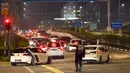 Polisi mengatur lalu lintas saat antrean panjang kendaraan untuk memasuki Woodlands Checkpoint sebelum melintasi jalan lintas ke Malaysia di Singapura, Jumat (1/4/2022). Singapura dan Malaysia kembali membuka perbatasannya untuk semua pelancong yang divaksinasi lengkap. (Roslan RAHMAN/AFP)