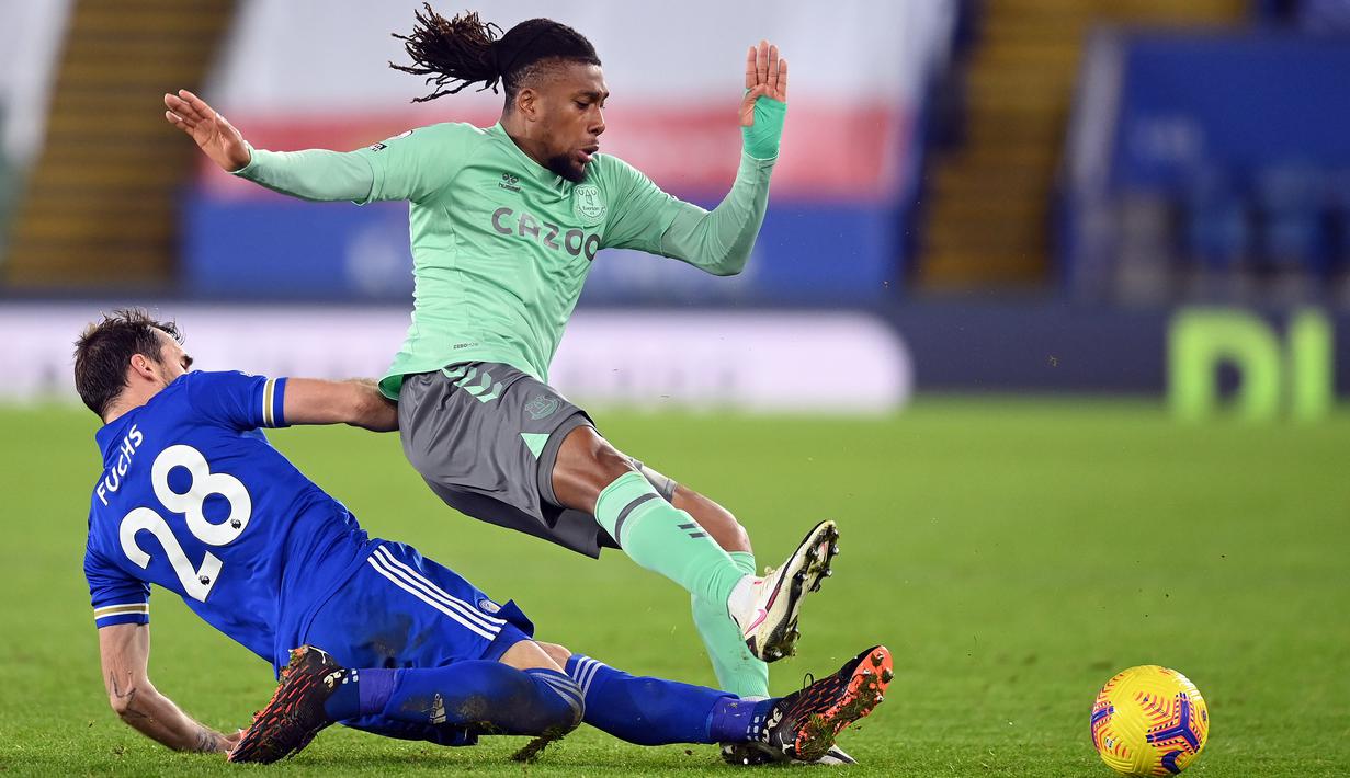 Gelandang Everton, Alex Iwobi, berebut bola dengan bek Leicester City, Christian Fuchs, pada laga lanjutan Liga Inggris di King Power Stadium, Kamis (17/12/2020) dini hari WIB. Everton menang 2-0 atas Leicester City. (AFP/Michael Regan/pool)