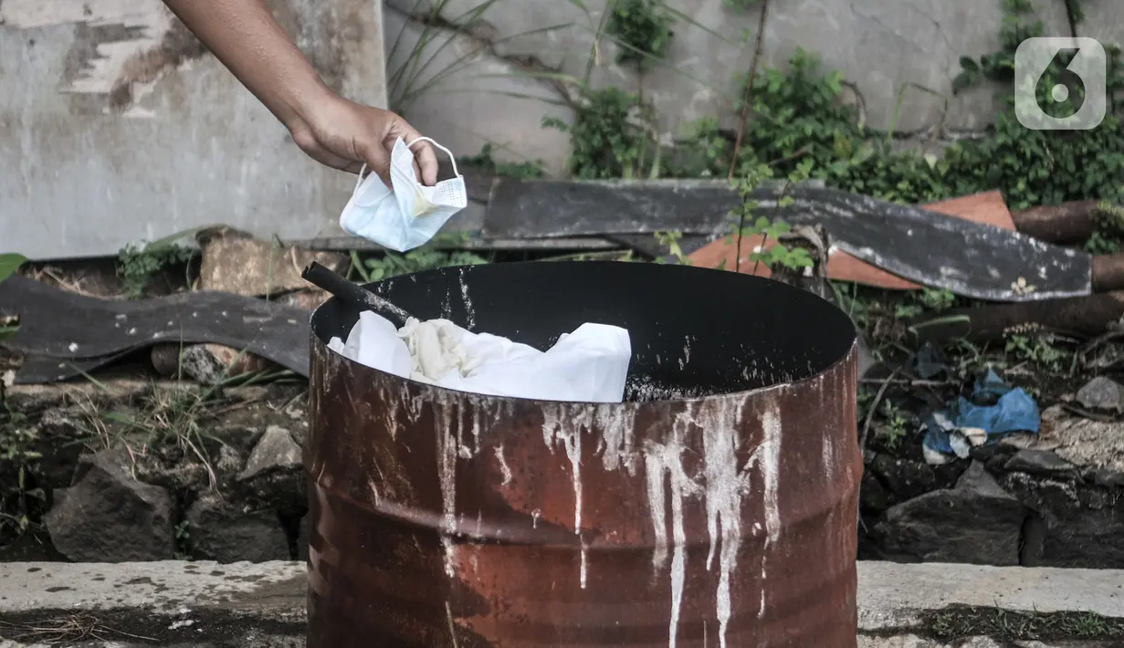 Sopir membuang masker dan alat pelindung diri usai bertugas mengantarkan pasien terpapar Covid-19 di Pool Unit Pelayanan Angkutan Sekolah (UPAS) DKI Jakarta, Kramat Jati, Selasa (5/1/2021). Usai bertugas, para sopir bus sekolah tersebut rutin melakukan dekontaminasi. (merdeka.com/Iqbal Nugroho)