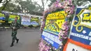 Tentara berjalan di samping karangan bunga ucapan bela sungkawa wafatnya Ani Yudhoyono menghiasi kawasan Puri Cikeas, Bogor, Jawa Barat, Minggu (2/6/2019). Ani Yudhoyono rencananya akan dimakamkan di TMP Kalibata pada siang ini. (Liputan6.com/Immanuel Antonius)