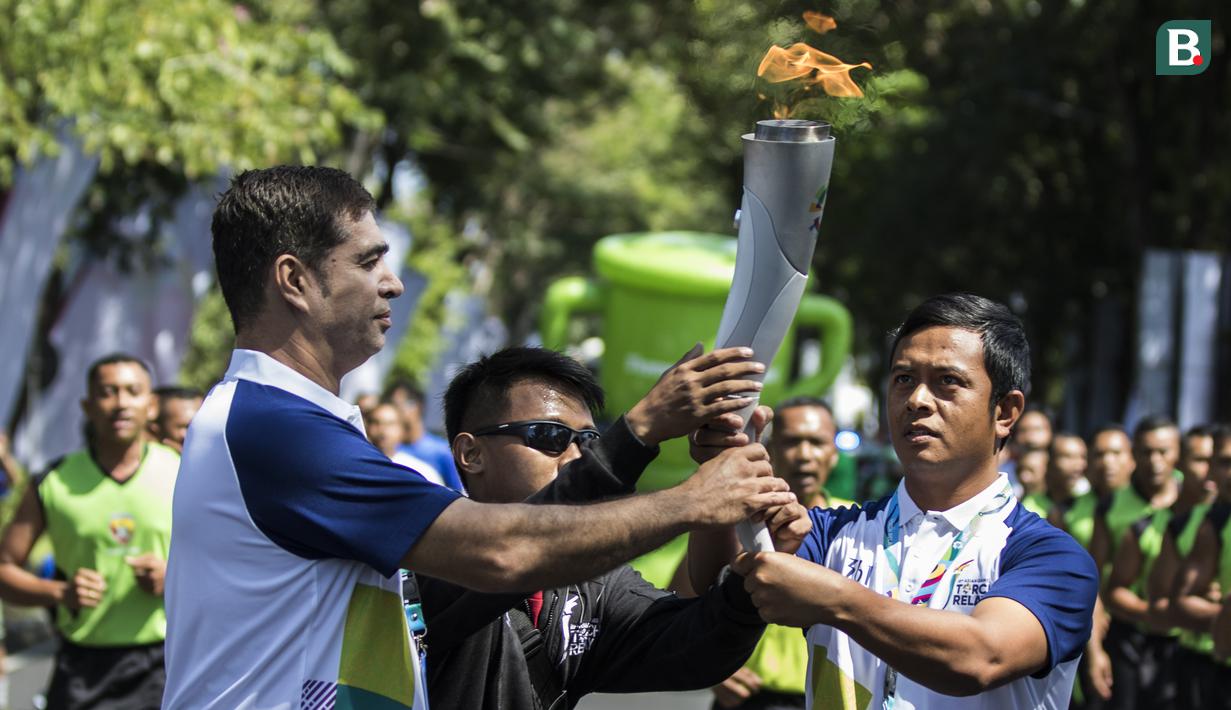 Pevoli legendaris Indonesia, Pascal Wilmar, menyerahkan obor Asian Games XVIII saat pawai di Denpasar, Bali, Selasa (24/7/2018). Sebanyak 53 kota di Indonesia akan dilalui oleh obor Asian Games. (Bola.com/Vitalis Yogi Trisna)