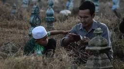 Muslim Thailand berdoa saat menziarahi kuburan kerabat mereka pada perayaan Idul Adha di provinsi Narathiwat, Minggu (11/8/2019). Pada setiap Idul Adha atau menyambut hari besar Islam sebagian warga banyak mendatangi kuburan untuk mendoakan keluarganya. (Madaree TOHLALA/AFP)