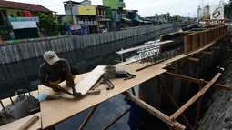 Pekerja melakukan pemasangan turap atau sheetpile Kali Item, Jakarta, Rabu (2/1). Turap sepanjang 1.900 meter pada sisi kanan dan kiri kali untuk mengantisipasi genangan dan banjir di kawasan tersebut pada musim hujan. (Merdeka.com/Imam Buhori)