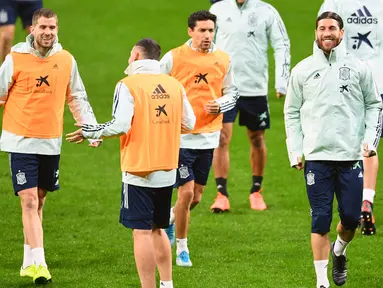 Bek Spanyol Sergio Ramos (kanan) tersenyum saat melakukan pemanasan selama sesi latihant tim di Stadion Wanda Metropolitano di Madrid (17/11/2019). Spanyol akan bertanding melawan Rumania pada Grup F Kualifikasi Piala Eropa 2020. (AFP Photo/Gabriel Bouys)