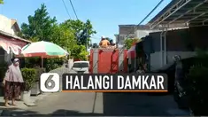 Petugas dan warga terpaksa bekerjasama mengangkat dan menggeser mobil tersebut untuk dimasukkan sementara ke garasi warga.