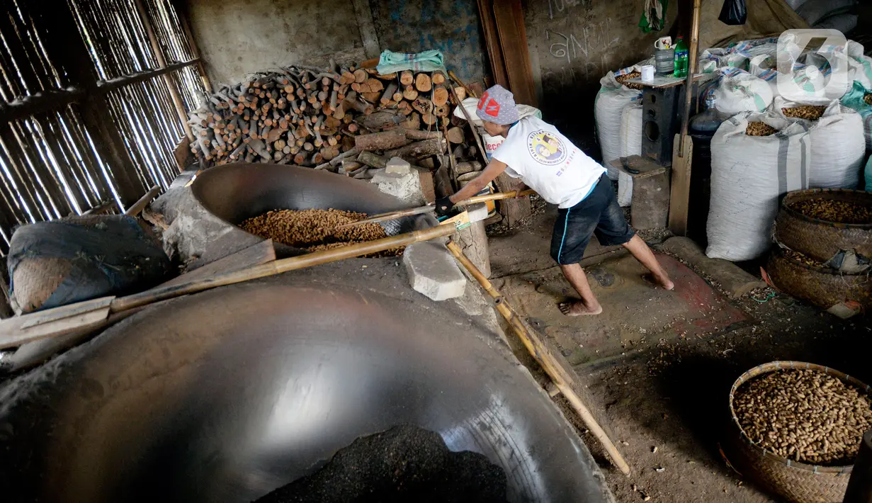 Pekerja mengolah kacang dengan media pasir di salah satu industri rumahan pembuatan kacang sangrai di Kawasan Keranggan, Tangerang Selatan, Selasa (11/8/2020). Kacang sangrai yang dipasarkan seharga Rp10.000 per kg itu mulai mengalami kenaikan pesanan dibanding bulan lalu. (merdeka.com/Dwi Narwoko)