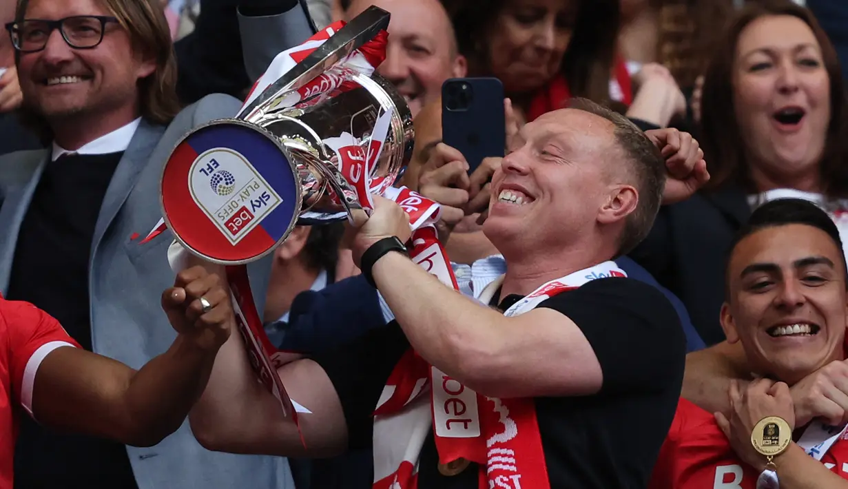 Pelatih Nottingham Forest, Steve Cooper mengangkat trofi usai mengalahkan Huddersfield Town pada final playoff divisi Championship di Stadion Wembley di London, Senin (30/5/2022). Nottingham Forest resmi kembali Premier League atau kasta tertinggi Liga Inggris usai absen selama 23 tahun. (AFP/Adrian Dennis)