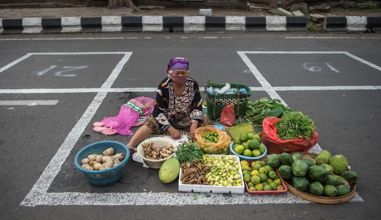 Pedagang menunggu pembeli di dalam garis petak-petak untuk menerapkan jaga jarak (physical distancing) di sepanjang jalan di Surabaya, Selasa (2/6/2020). Garis petak-petak bagi pedagang itu sebagai langkah pencegahan penyebaran COVID-19. (Photo by Juni Kriswanto / AFP)