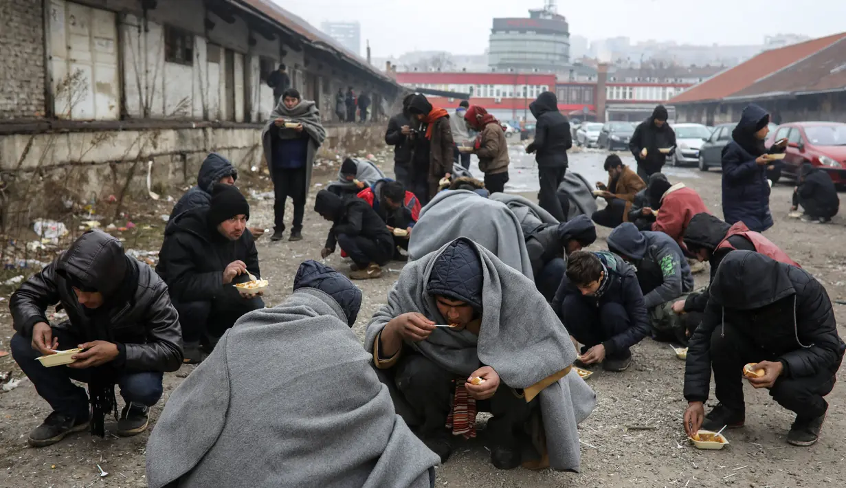 Sejumlah imigran makan makanan yang dibagikan secara gratis di Belgrade, Serbia, Kamis (22/12). (REUTERS / Marko Djurica)