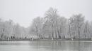 Orang-orang berjalan saat salju turun di Taman Retiro di pusat kota Madrid (7/1/2021). Pihak berwenang menyarankan warga untuk menghindari perjalanan darat di daerah dengan peringatan kondisi cuaca buruk. (AFP/Gabriel Bouys)