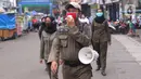 Petugas Satpol PP mengimbau warga untuk menggunakan masker dan menjaga jarak di Pasar Lama, Kota Tangerang, Banten, Sabtu (9/6/2020). Pemkot Tangerang melakukan penegasan pada PSBB tahap dua dengan menugaskan petugas di keramaian guna memutus rantai penyebaran COVID-19.  (Liputan6.com/Angga Yuniar)