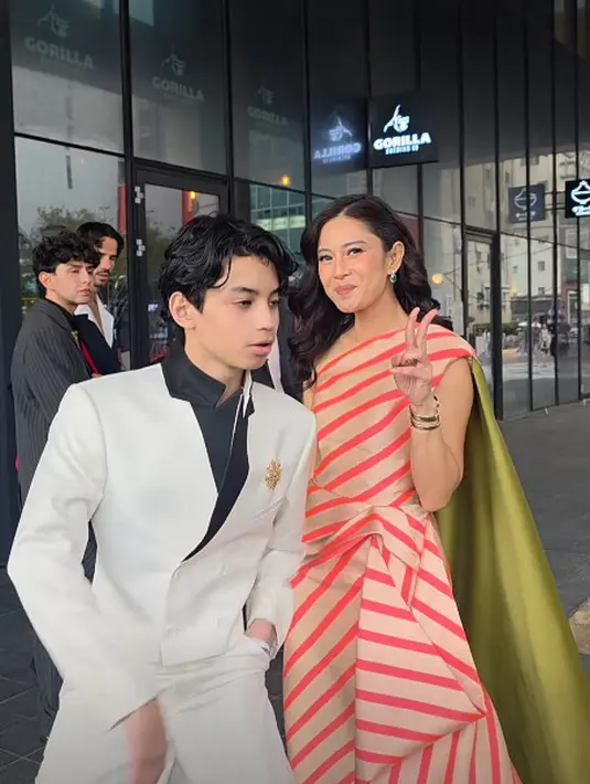 Gaun ini dilengkapi aksen cape lebar dual tone yang dijepit di jari kanan. Bikin penampilan Dian terlihat megah [@therealdisastr]