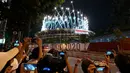 Orang-orang mengambil foto di luar saat kembang api menerangi langit di atas Stadion Olimpiade selama upacara pembukaan Paralimpiade Tokyo 2020 di Tokyo pada 24 Agustus 2021. (AFP/Kazuhiro Nogi)