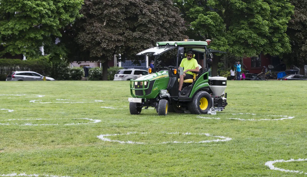 Pekerja menggambar lingkaran putih di Taman Trinity Bellwoods, Toronto, Kanada, Kamis (28/5/2020). Taman Trinity Bellwoods digambari lingkaran-lingkaran putih sebagai proyek uji coba untuk mendorong warga melakukan jaga jarak fisik (physical distancing) selama pandemi COVID-19. (Xinhua/Zou Zheng)