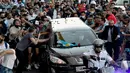 Para penggemar berkerumun di samping mobil jenazah yang membawa mendiang legenda sepak bola Argentina, Diego Maradona menuju pemakaman, di Buenos Aires, Kamis (26/11/2020).  Maradona meninggal dunia dalam usia 60 tahun pada Rabu (25/11) karena serangan jantung. (Raul FERRARI/TELAM/AFP)