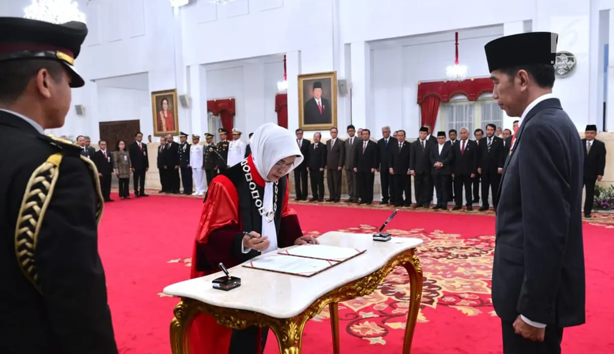 Hakim Mahkamah Konstitusi (MK) yang baru, Enny Nurbaningsih menandatangani dokumen disaksikan Presiden Joko Widodo selama pelantikan menjadi hakim Mahkamah Konstitusi (MK) di Istana Negara, Jakarta, Senin (13/8). (Liputan6.com/Biropers)