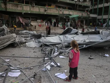 Seorang anak perempuan Palestina melihat reruntuhan sekolah Fatima Bint Asad yang dihantam serangan semalam oleh Israel di Jabalia, Jalur Gaza utara, Senin 12 Mei 2025. (Bashar TALEB/AFP)