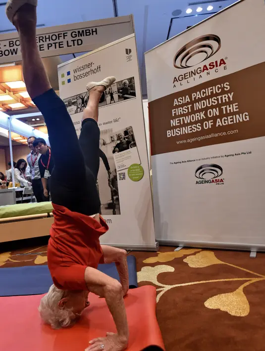 Pesenam tertua di dunia asal Jerman, Johanna Quaas (92) melakukan gerakan bertumpu pada kepala saat Forum Inovasi Aging Asia Internasional ke-8 di Singapura, Selasa (25/4). (AFP PHOTO / ROSLAN RAHMAN)
