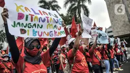 Massa buruh perempuan membentangkan poster tuntutan saat turut dalam aksi menolak UU Cipta Kerja di kawasan Patung Kuda, Jakarta, Selasa (10/11/2020). Dalam aksinya massa buruh mendesak Presiden Jokowi untuk membatalkan UU Cipta Kerja. (merdeka.com/Iqbal S. Nugroho)