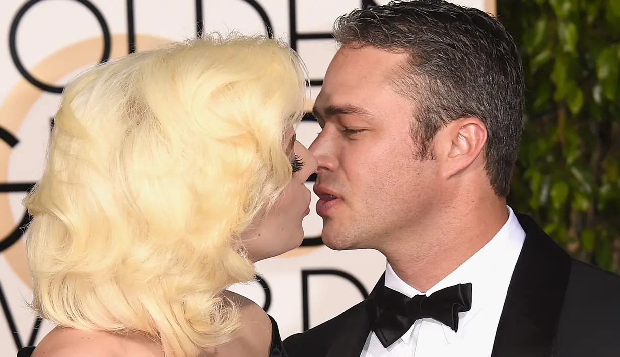 Penyanyi Lady Gaga dan sang tunangan, Taylor Kinney saling berciuman dengan mesra saat ditengah-tengah sesi foto ajang penghargaan film tahunan, Golden Globes 2016 di Beverly Hilton Hotel, California, Minggu (10/1). (Jason Merritt/Getty Images/AFP)