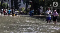 Warga melintasi genangan air yang merendam jalan di kawasan Kampung Makasar, Jakarta Timur, Senin (7/7/2025). (Liputan6.com/Herman Zakharia)