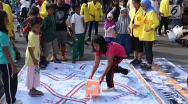 Mahasiswa jurusan Kriminologi Fisip UI mendampingi anak-anak bermain ular tangga saat gelaran Car Free Day di kawasan Bundaran HI, Jakarta, Minggu (18/11). Permainan ini bertujuan mengurangi anak-anak bermain gawai. (Liputan6.com/Helmi Fithriansyah)